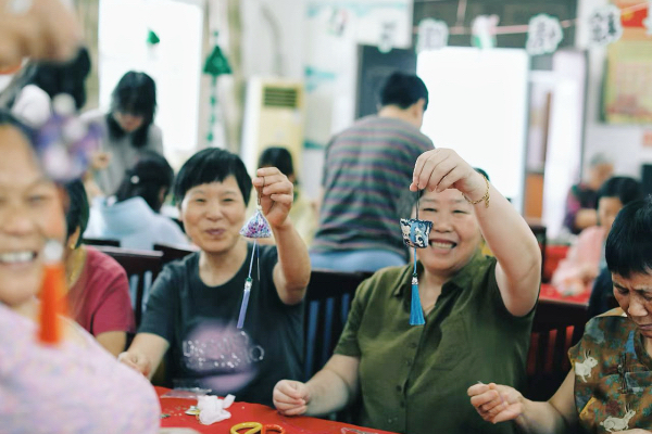 夏至时节，社区居民齐聚一堂手工缝制驱蚊香包，大家举着成品笑容满面，同心共享美好生活。舟山市普陀区纪委监委 朱贝儿 摄.png